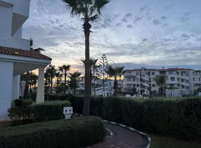 a palm tree in front of a building at Garden beach 2 in Sidi Rahal