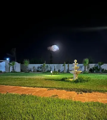 a fire hydrant in the middle of a yard at night at la ferme du bonheur in Aïn el Apuda