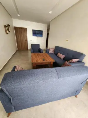 a living room with a blue couch and a wooden table at Apparemment de détente in Mansouria