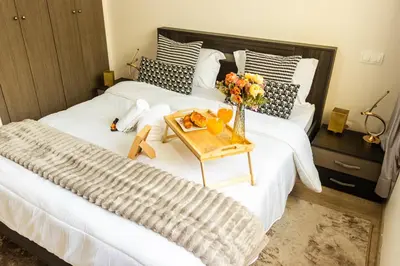 a white bed with a vase of flowers on it at VIVASTAY Casablanca - Charming Studio Nouacer - 4 min Airport Mohamed V CMN in Nouaseur
