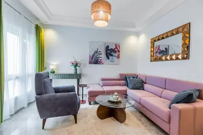 a living room with a pink couch and two chairs at chic & cozy Apartment, Parc Serenity in Mohammedia