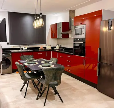 a kitchen with red cabinets and a table and chairs at Chic, well-equipped apartment in a perfect location in Temara