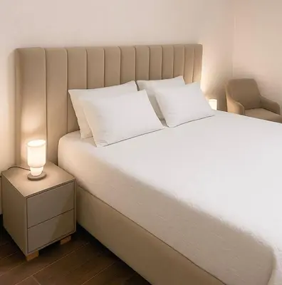 a bed with white pillows and a lamp on a night stand at Chic, well-equipped apartment in a perfect location in Temara