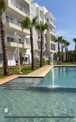 a swimming pool with a fountain in front of a building at Luxe appartement in Bouznika