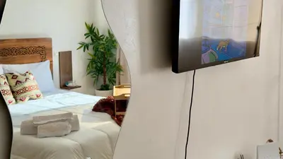 a bedroom with a bed and a tv on a wall at Charming City Retreat in Agdal - Walk to Train Station in Rabat