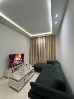 a living room with a green couch and a tv at Petit bijou à Hay Riad in Rabat