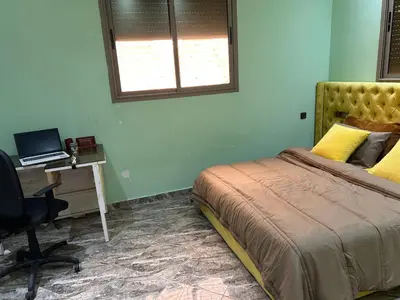 a bedroom with a bed and a desk with a laptop at Appartment calme a Ain Aouda in Aïn el Apuda