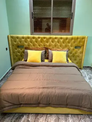 a large bed with a yellow headboard in a room at Appartment calme a Ain Aouda in Aïn el Apuda