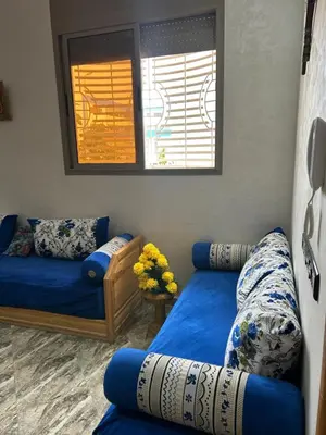 a living room with two blue couches and a window at Appartment calme a Ain Aouda in Aïn el Apuda