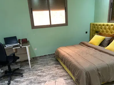 a bedroom with a bed and a desk with a laptop at Appartment calme a Ain Aouda in Aïn el Apuda