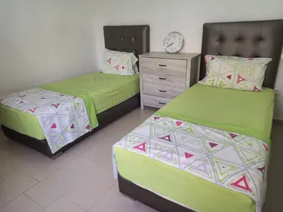 two beds in a room with a clock on the wall at Résidence balnéaire - Piscine Plage et Diverses in Sidi Rahal