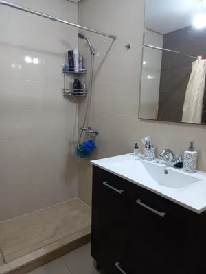 a bathroom with a sink and a shower with a mirror at Résidence balnéaire - Piscine Plage et Diverses in Sidi Rahal