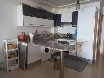 a kitchen with white cabinets and a granite counter top at Résidence balnéaire - Piscine Plage et Diverses in Sidi Rahal
