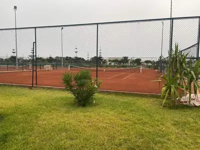 a tennis court with two tennis courts at Résidence balnéaire - Piscine Plage et Diverses in Sidi Rahal