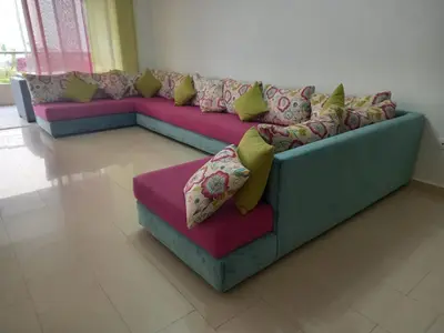 a couch with pillows on it in a room at Résidence balnéaire - Piscine Plage et Diverses in Sidi Rahal
