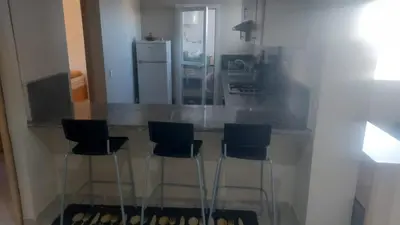 a kitchen with a counter with three stools at La vie de vacances fal azur in Bouznika
