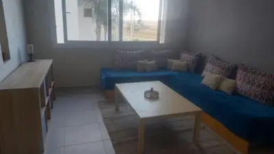 a living room with a blue couch and a table at La vie de vacances fal azur in Bouznika
