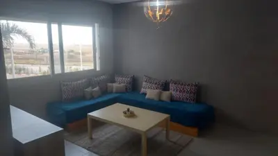 a living room with a blue couch and a table at La vie de vacances fal azur in Bouznika