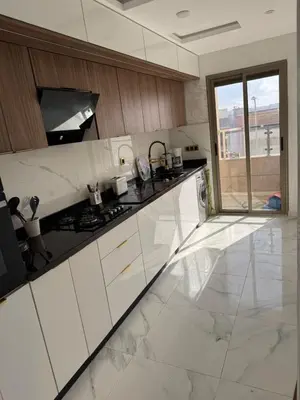 a white kitchen with a stove and a window at Appartement à Dahomey - Bouznika in Bouznika