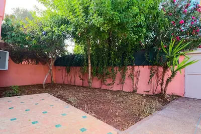 a garden with trees and a pink fence at Casa Nova Maison moderne à deux pas de la plage in Bouznika