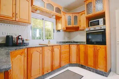 a kitchen with wooden cabinets and a window at Casa Nova Maison moderne à deux pas de la plage in Bouznika