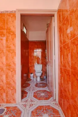 a bathroom with a toilet in an orange wall at Casa Nova Maison moderne à deux pas de la plage in Bouznika