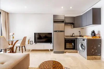 a kitchen with stainless steel appliances and a living room at 1- Bourgogne City Escape in Casablanca