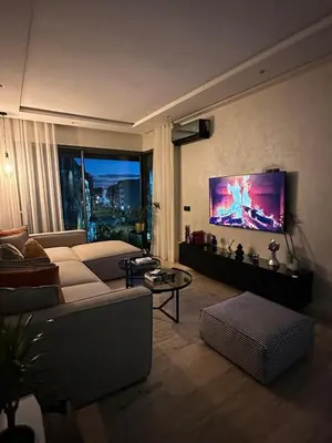 a living room with a couch and a tv on the wall at Cosy Family 2BR Apartment - Terrace & Sunset Views in Casablanca