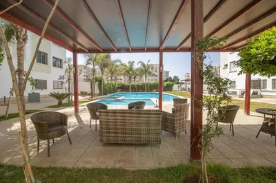 a patio with a table and chairs and a swimming pool at Calme & Cocon Apartment Near Airport in Nouaceur