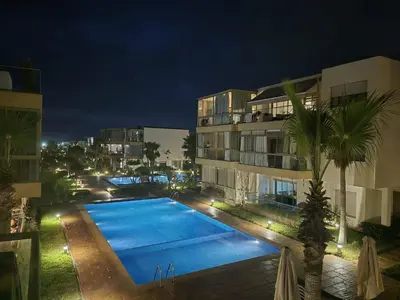 a swimming pool in front of a building at night at Appart pour Famille balnéaire Accés direct à la Mer in Sidi Rahal