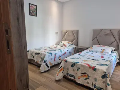 a bedroom with two beds and a door with a door at Appart pour Famille balnéaire Accés direct à la Mer in Sidi Rahal