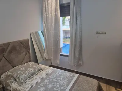 a bedroom with a bed and a window with a pool at Appart pour Famille balnéaire Accés direct à la Mer in Sidi Rahal