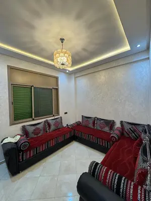 a living room with red couches and a chandelier at 3 bedroom apartment with living room and terrace 90metre in El Harhoura