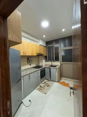 a kitchen with wooden cabinets and a tile floor at 3 bedroom apartment with living room and terrace 90metre in El Harhoura