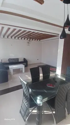 a dining table and chairs in a living room at Résidence yassine in Rabat