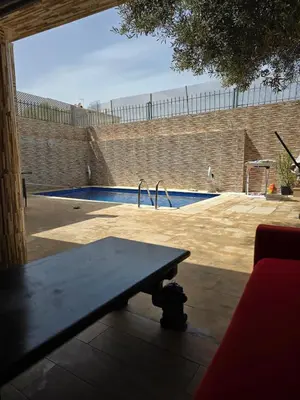 a wooden bench sitting in front of a swimming pool at Appartement villa in Temara