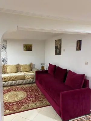 a living room with a purple couch and a rug at Appartement villa in Temara