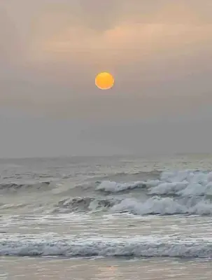 a sun is in the sky over the ocean at Blue Beach in Sidi Rahal