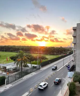 a street with cars driving down a road with a sunset at CityCore duplex in Casablanca