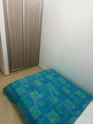 a bed with a blue and green comforter in a room at Appartement Sidi Rehal beach in Sidi Rahal