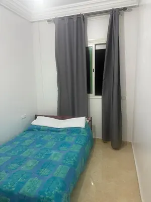 a bedroom with a bed and a window with curtains at Appartement Sidi Rehal beach in Sidi Rahal