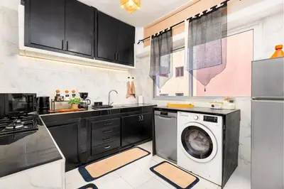a kitchen with black cabinets and a washing machine at Bright apartment Maarif, 2 bedrooms, Wi-Fi, AC in Casablanca