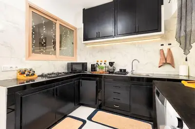 a kitchen with black cabinets and a sink at Bright apartment Maarif, 2 bedrooms, Wi-Fi, AC in Casablanca
