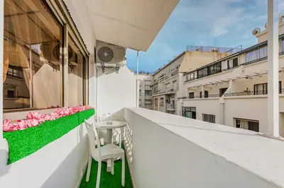 a white chair sitting on a balcony with pink flowers at Bright apartment Maarif, 2 bedrooms, Wi-Fi, AC in Casablanca