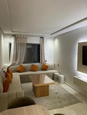 a living room with a couch and a tv at Résidence Beach Land El Mansouria in Mohammedia