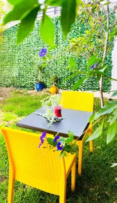 a yellow table and chairs in a yard with flowers at Stunning Sunny Villa, near airport in Derroua