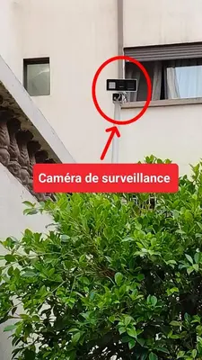 a sign that says camera be surveillance next to a tree at Bel appartement in Casablanca