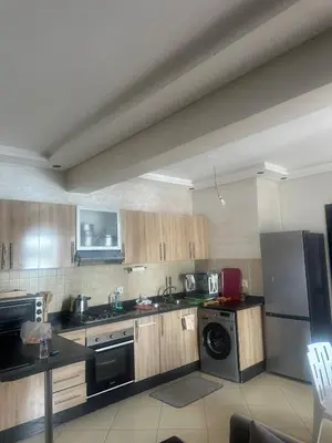 a kitchen with wooden cabinets and a washer and dryer at New and cosy appt for rent in Sidi Rahal
