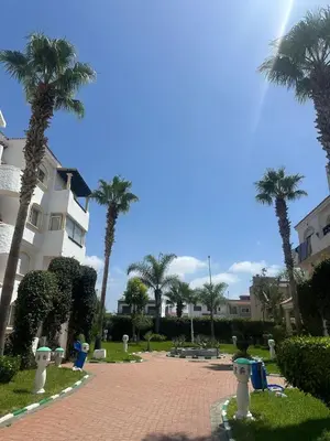 a park with palm trees in front of a building at New and cosy appt for rent in Sidi Rahal