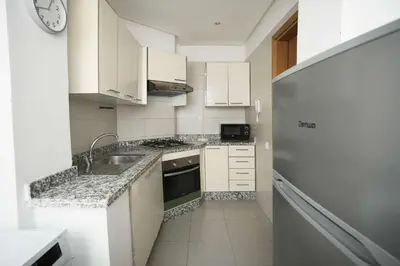 a kitchen with white cabinets and a sink and a refrigerator at Comfortable Getaway Near the Beach in Dar Bouazza
